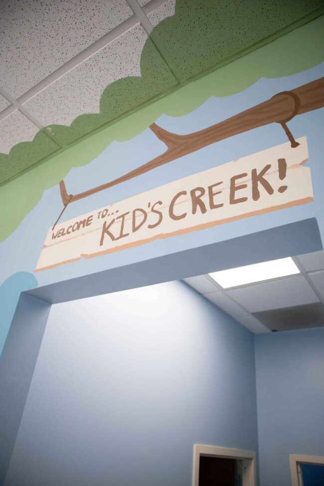 Kid's Creek Therapy - A graphic of a sign on a tree in the forest reads "Welcome to Kid's Creek" and decorates the walls of the Kid's Creek office