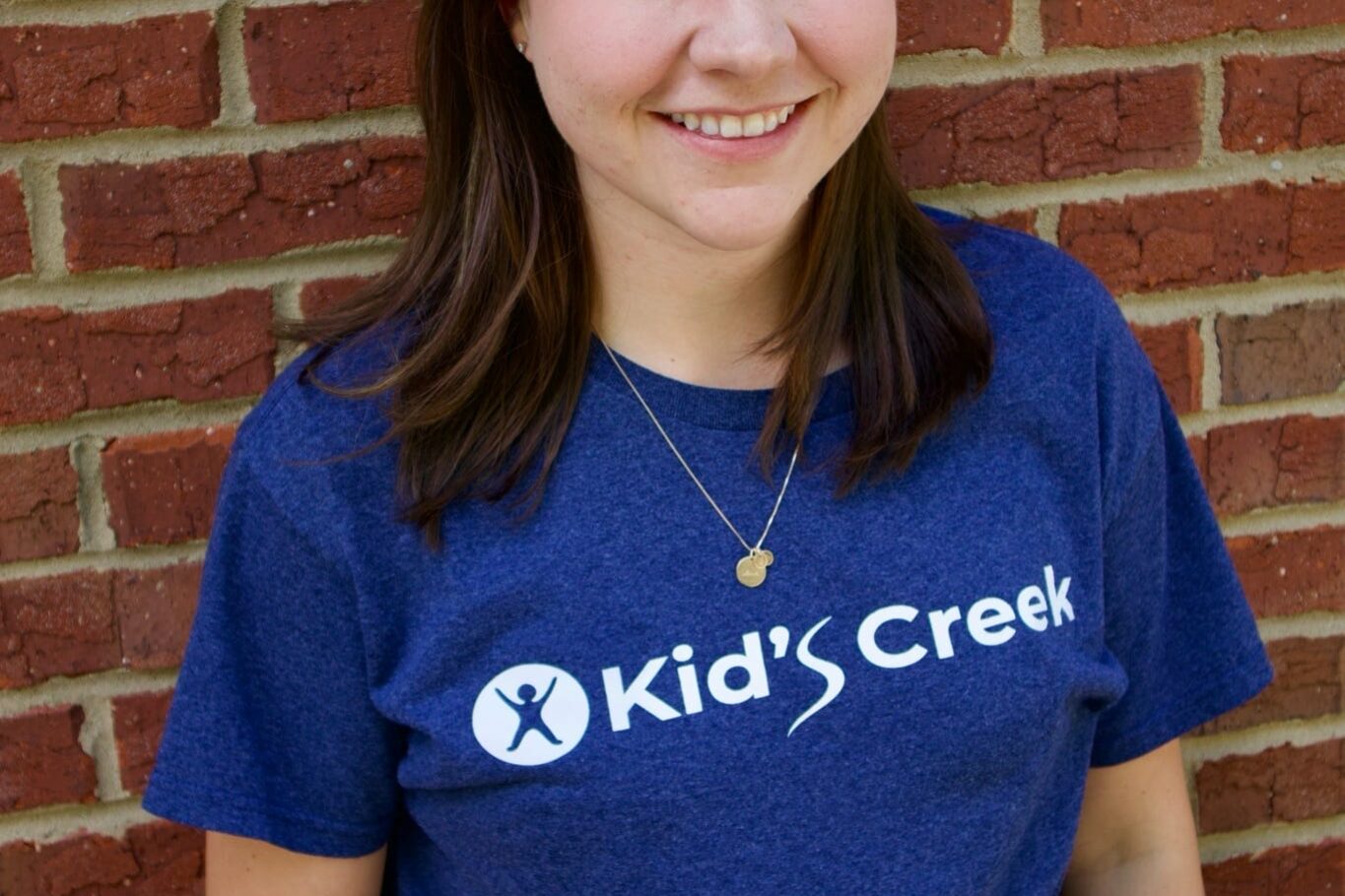 Kid's Creek Therapy - Employee poses for headshot with brick wall in background