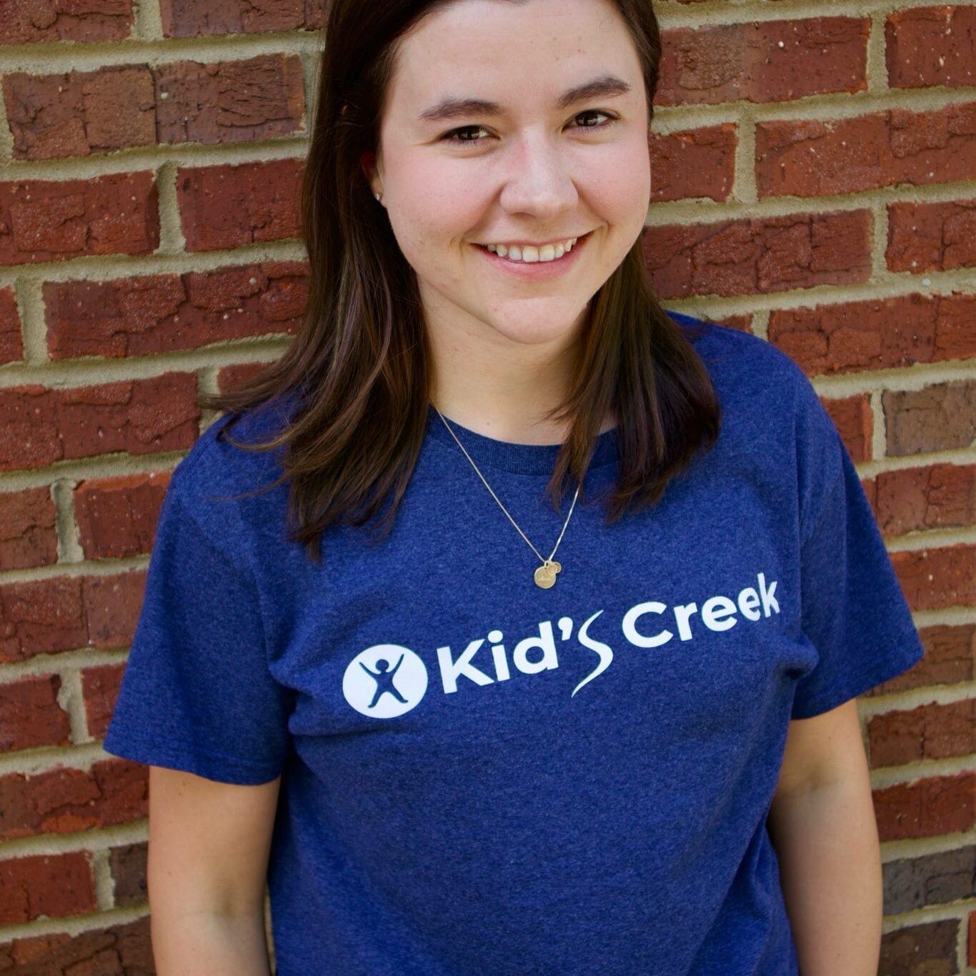 Kid's Creek Therapy - Employee poses for headshot with brick wall in background