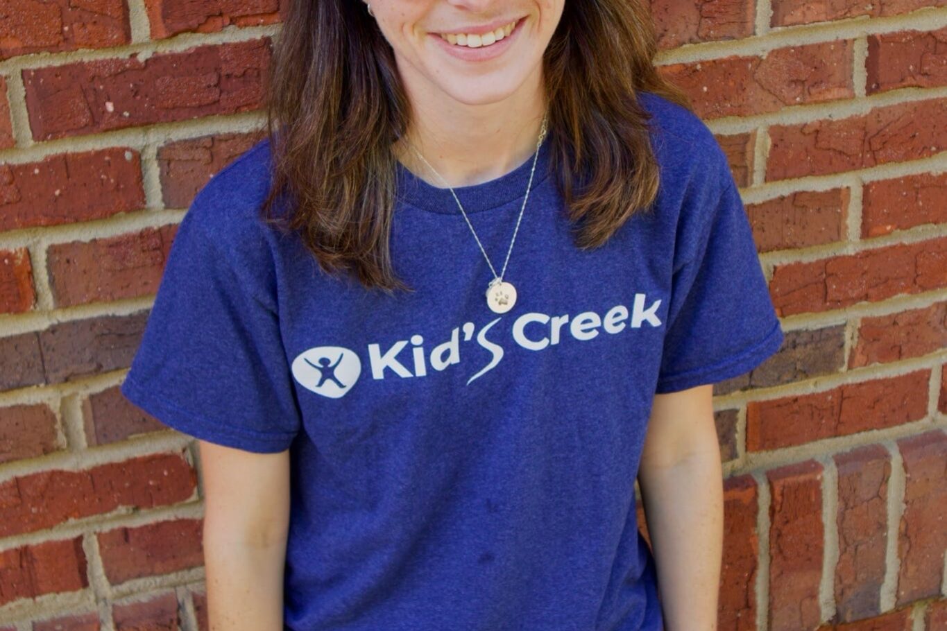 Kid's Creek Therapy - Employee poses for headshot with brick wall in background