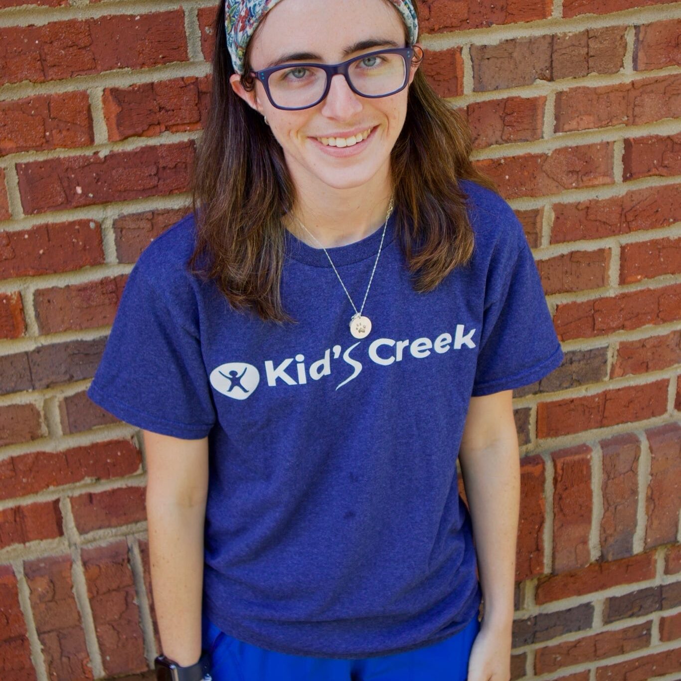 Kid's Creek Therapy - Employee poses for headshot with brick wall in background