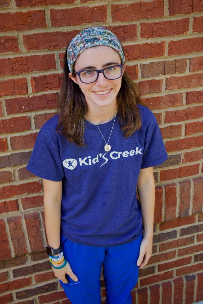 Lindsey Kid's Creek Therapy - Employee poses for headshot with brick wall in background