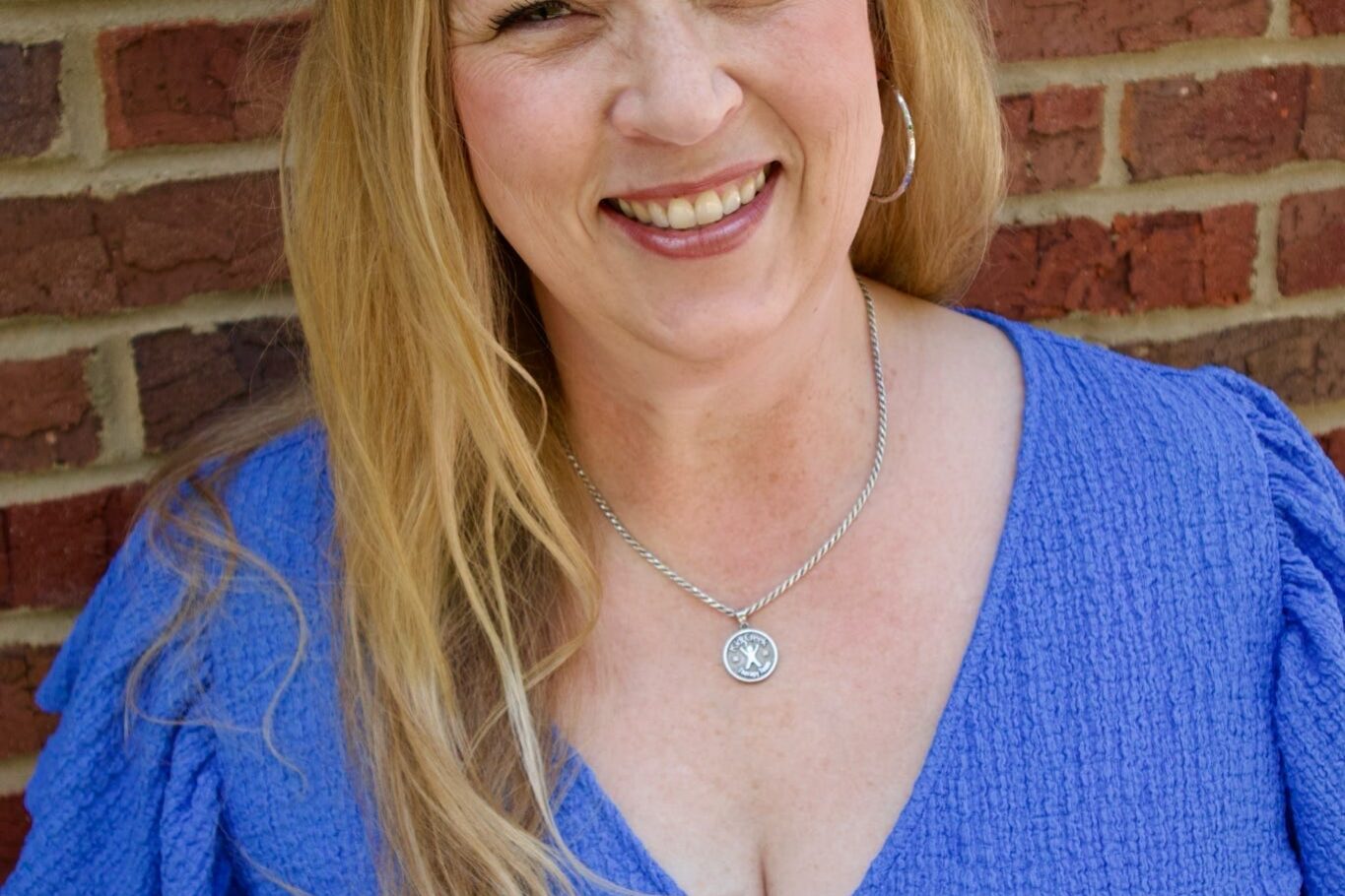 Kid's Creek Therapy - Employee poses for headshot with brick wall in background