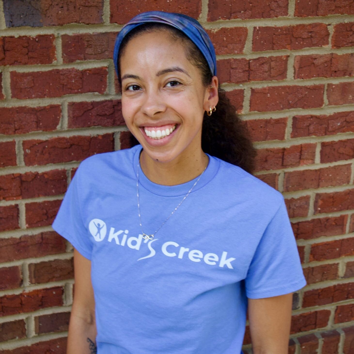 Kid's Creek Therapy - Employee poses for headshot with brick wall in background