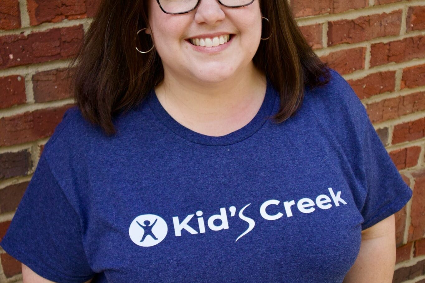 Kid's Creek Therapy - Employee poses for headshot with brick wall in background