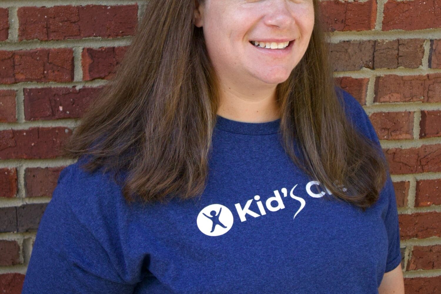 Kid's Creek Therapy - Employee poses for headshot with brick wall in background