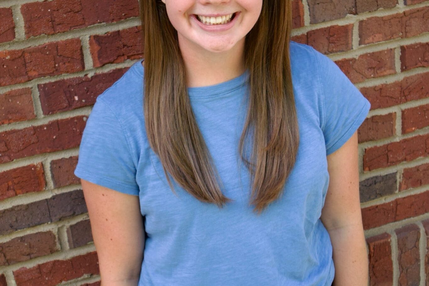 Kid's Creek Therapy - Employee poses for headshot with brick wall in background