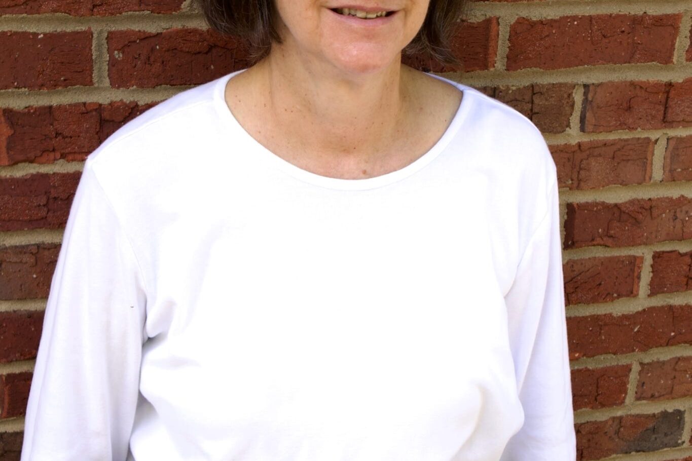Kid's Creek Therapy - Employee poses for headshot with brick wall in background