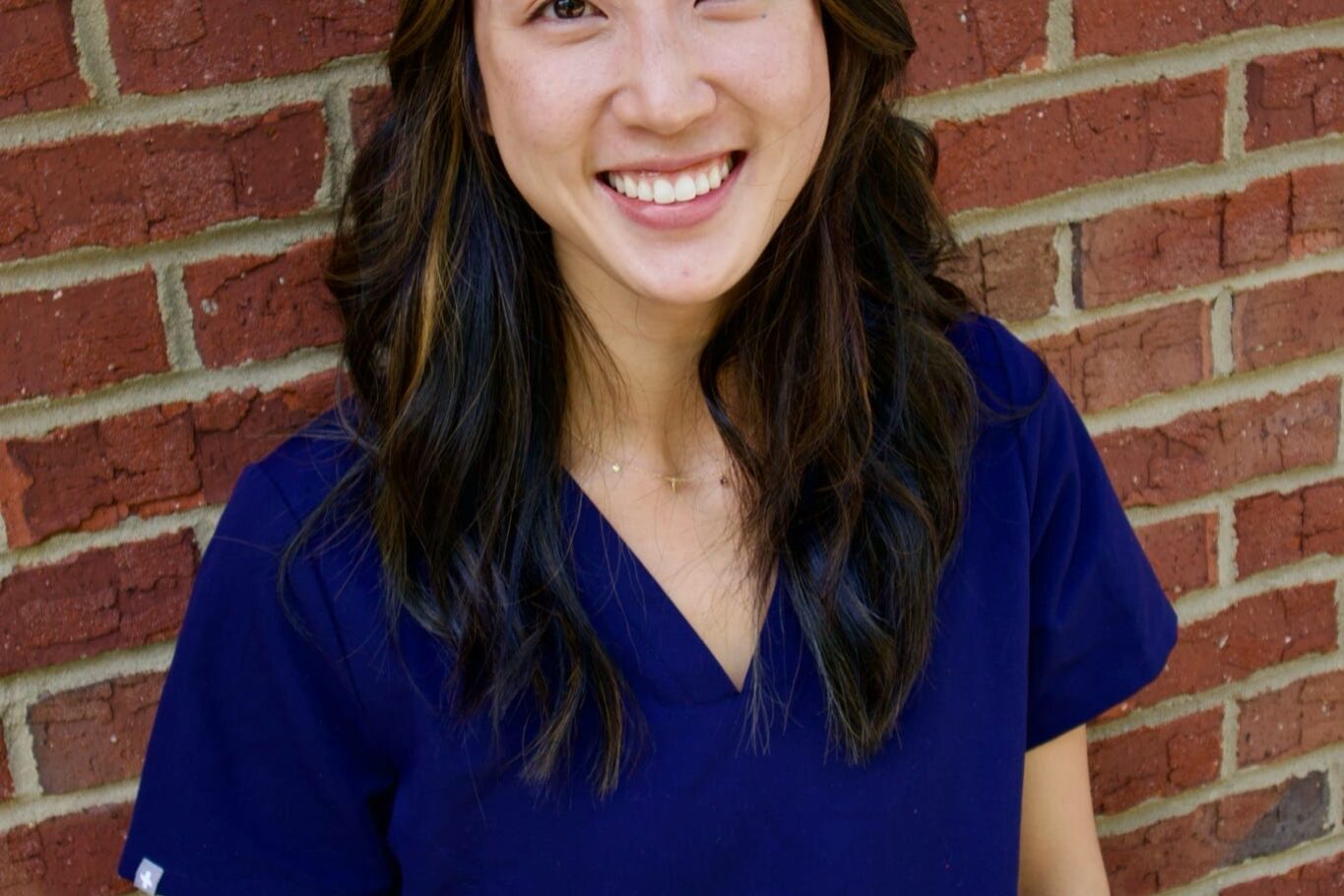 Kid's Creek Therapy - Employee poses for headshot with brick wall in background