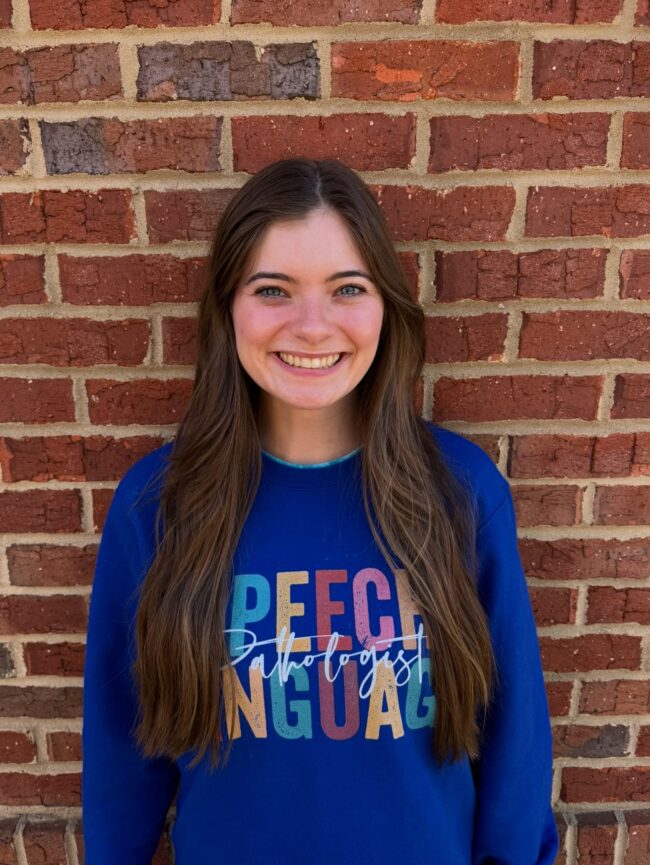 Lizzy Kid's Creek Therapy - Employee poses for headshot with brick wall in background