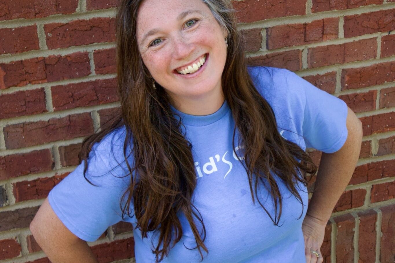 Kid's Creek Therapy - Employee poses for headshot with brick wall in background